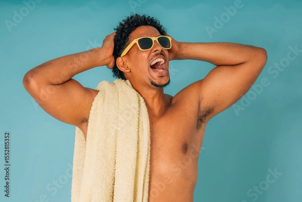 Obraz young latino man shouting with sunglasses and towel in swimsuit isolated on background, summer