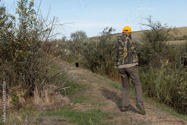 Fototapeta Hunter aiming with rifle while standing against sky
