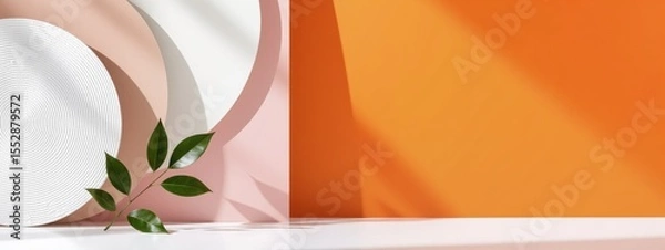 Obraz Green leaves on a branch with abstract pastel and white shapes, casting shadows on a bright orange background. Minimalist natural product display.