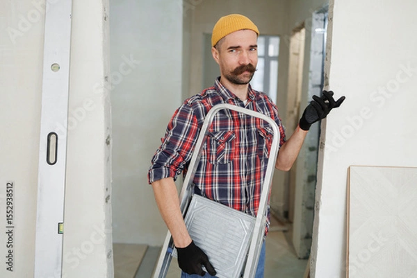 Fototapeta construction worker guy with a drill on a white wall background.master for an hour.