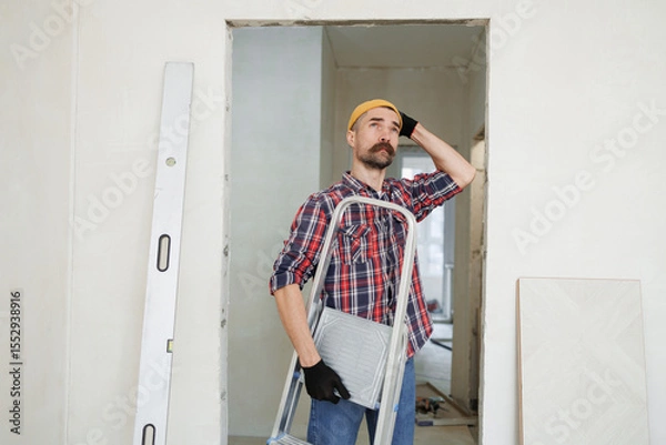 Fototapeta construction worker guy with a drill on a white wall background.master for an hour.