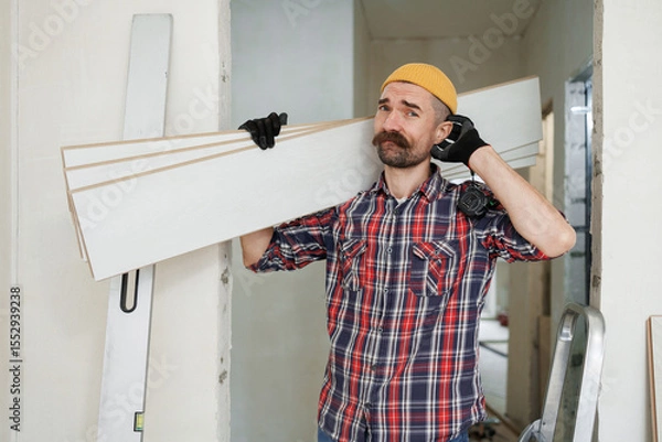 Fototapeta construction worker guy with a drill on a white wall background.master for an hour. construction worker guy with a drill on a white wall background.master for an hour. laying laminate flooring in an a