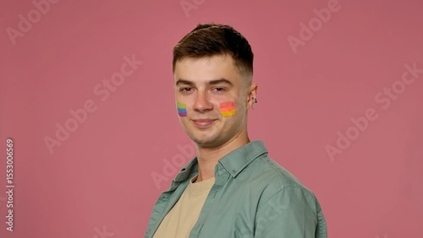 Fototapeta Man with Rainbow Face Paint Smiling Against Pink Background