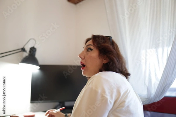 Fototapeta Woman working from home is having a revelation while taking notes