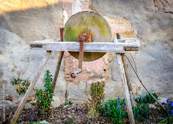 Fototapeta Historical stone wheel used for grinding grains in a rustic farming setting during daylight hours in an outdoor environment