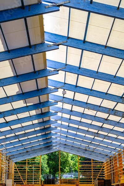 Fototapeta Construction progress of a building with exposed roof structure showcasing modern architectural design under clear blue sky
