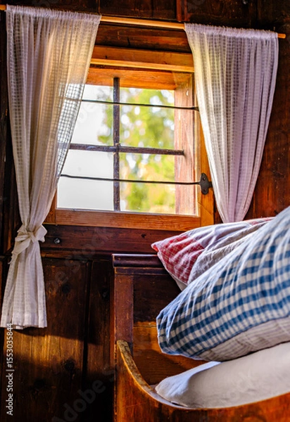 Fototapeta Cozy bed with checkered pillows in a rustic wooden cabin during a serene afternoon