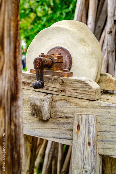 Fototapeta Historical stone wheel used for grinding grains in a rustic farming setting during daylight hours in an outdoor environment