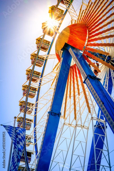 Fototapeta Ferris wheel illuminated at dusk with vibrant colors against a cloudy sky in a festive atmosphere