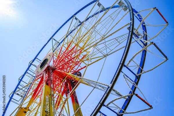 Fototapeta Ferris wheel illuminated at dusk with vibrant colors against a cloudy sky in a festive atmosphere