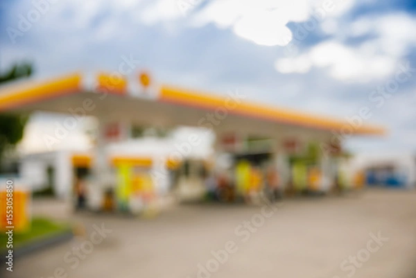 Obraz Defocused image of modern gas station with yellow and orange canopy under blue sky