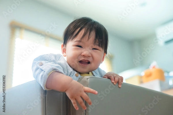 Fototapeta Baby 8 months try to climb escapes from the playpen. The child proud and happy to climbs the playpen successfully.