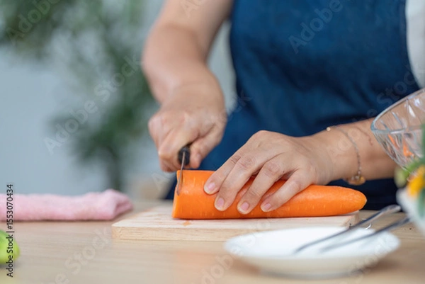 Obraz Healthy Cooking and Meal Prep. A person slicing a carrot in a modern kitchen setting.