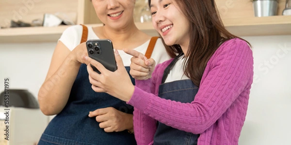 Obraz Exploring Recipes: Women Engaged with Smartphone in Kitchen