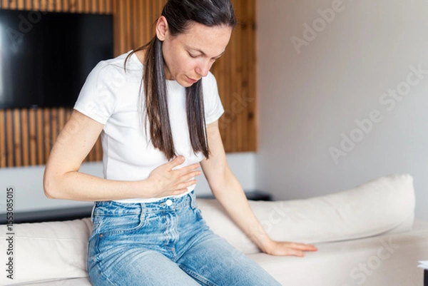 Obraz Woman experiences discomfort due to chronic illness while sitting at home