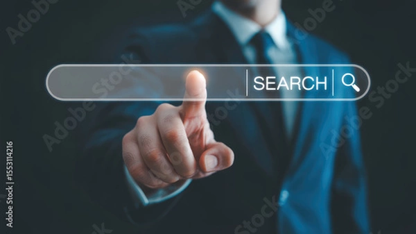Fototapeta A man in a suit is pointing to a search bar on a computer screen. Concept of professionalism and focus, as the man is likely working on a task that requires him to search for information
