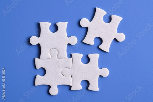 Obraz Four puzzle pieces on blue background. The concept of finding the right solutions in teamwork.