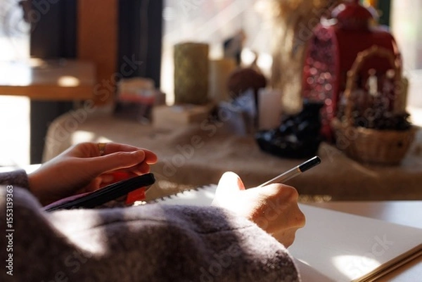 Fototapeta Warm sunlight filters through a window as hands sketch ideas in a serene and inviting environment.