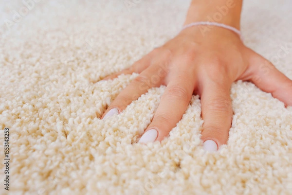 Obraz a woman's hand touching the beige Interior pile carpet made of polypropylene.