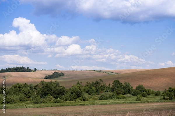 Fototapeta A magical landscape. Rural landscape with a hill and clouds. White fluffy clouds in the sky.