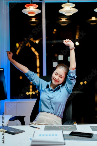 Fototapeta Smiling female programmer relaxing late at night with completed work. Software developer working on new project in office.