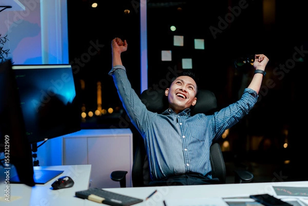 Fototapeta Male programmer relaxes late at night with completed work. Software developer working on new project in office.