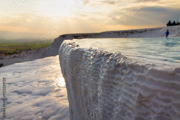Obraz Pamukkale, Turkey: Sunset illuminates white travertine terraces and thermal pool. Unique geological formations created by mineral-rich geothermal waters flowing down natural cascades. 