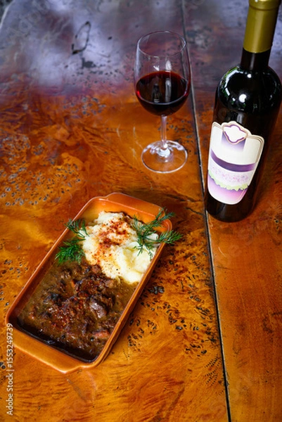 Fototapeta Venison stew with mashed potatoes with a bottle and a glass of wine