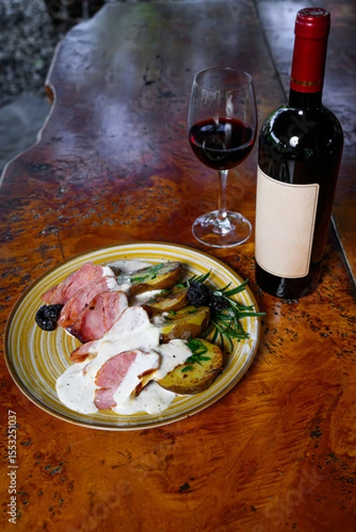 Fototapeta Pork fillet with potatoes and sauce wwith a bottle and a glass of wine