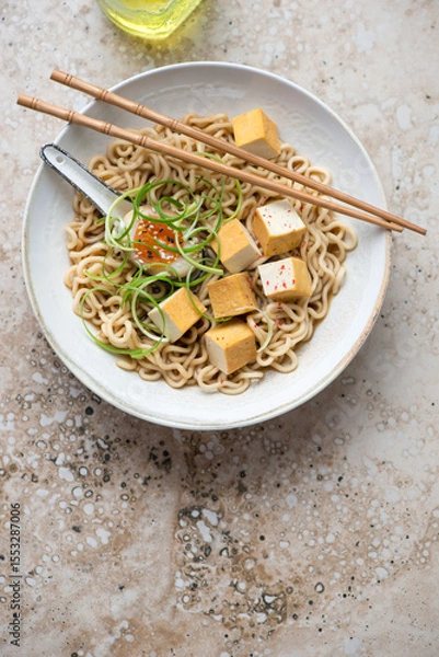 Fototapeta Ramen with marinated egg, smoked tofu and spring onion, vertical shot on a beige granite background with space, flat lay
