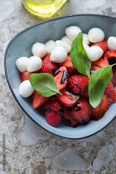 Fototapeta Bowl of caprese with fresh strawberry, mini mozzarella, fresh basil and balsamic vinegar, vertical shot, middle close-up