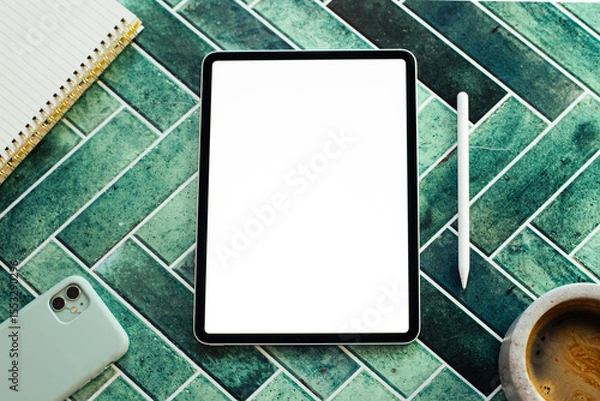 Obraz Top view of a digital creative workspace featuring a blank screen tablet, stylus, notebook, smartphone, and a cup of coffee on a stylish green tile surface. Ideal for concepts like remote work