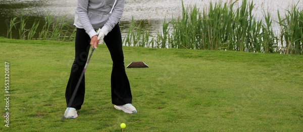 Obraz Female Golfer Preparing to Swing at a Tournament Near a Pond