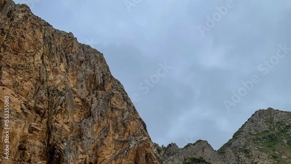 Fototapeta Rugged cliffs ascend majestically under a brooding sky, hinting at ancient tales of Earth Day and Fengari's Night