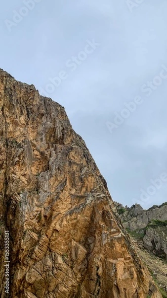 Fototapeta Rugged cliffs tower solemnly against an overcast sky, evoking adventure on Earth Day and the whimsical spirit of Geologist Day