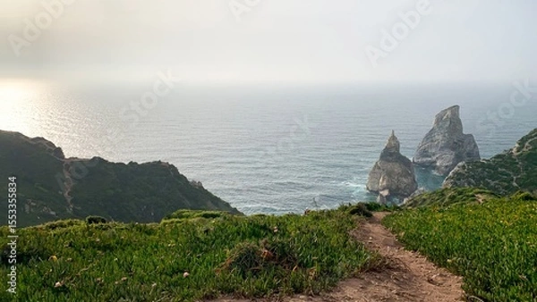 Fototapeta A winding path leads to jagged cliffs embracing the sea, perfect for Earth Day reflections and coastal meditations