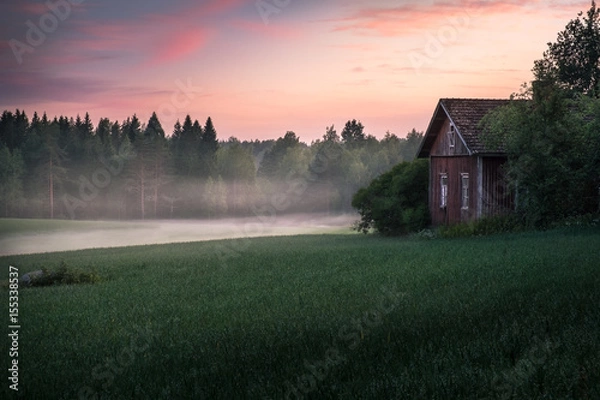 Fototapeta Scenic landscape with field and old cottage at summer night in Finland