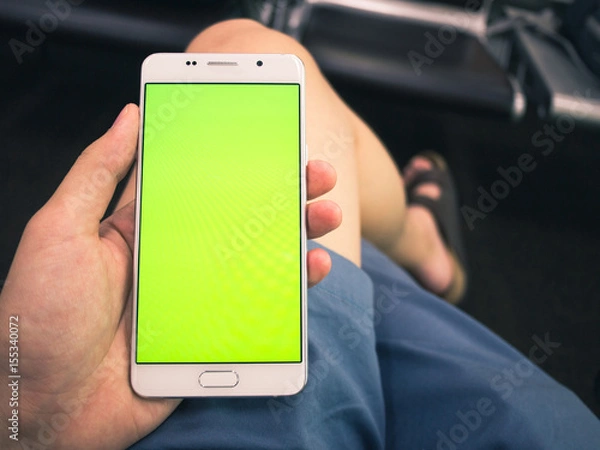 Fototapeta A man holding smartphone with green keyed out screen