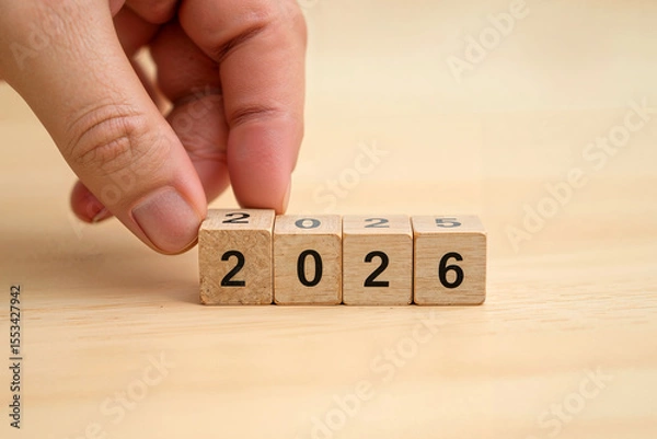 Obraz A hand moving wooden blocks with Loading bar between 2025 and 2026