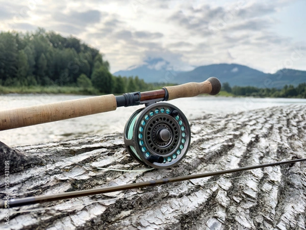Fototapeta Fishing fly reel and pole facing sideways on log with Skagit river and mountains