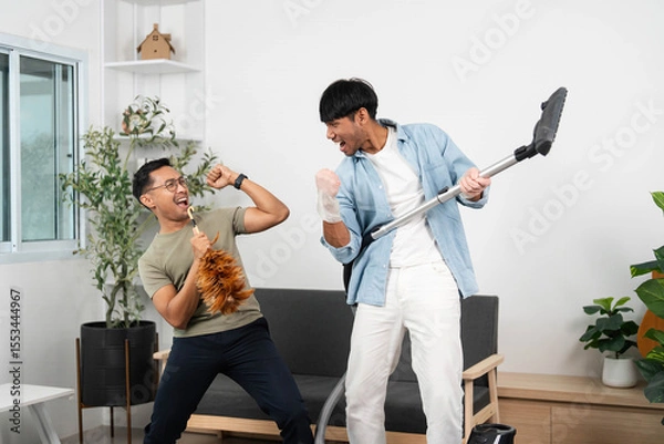 Obraz Playful cleaning moment. Two friends having fun while vacuuming and enjoying their time together.