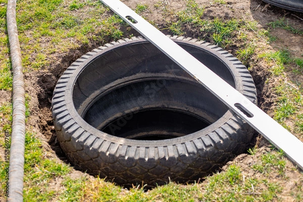 Fototapeta A pit for an outdoor village toilet with walls made of rubber tires. Making a toilet on a personal plot
