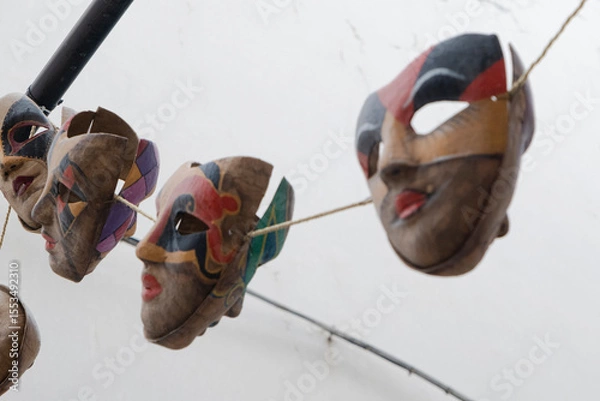 Obraz Traditional carnival masks hanging on clothesline against white sky. Colorful papier-mâché faces with expressive features showcase European folk art.
