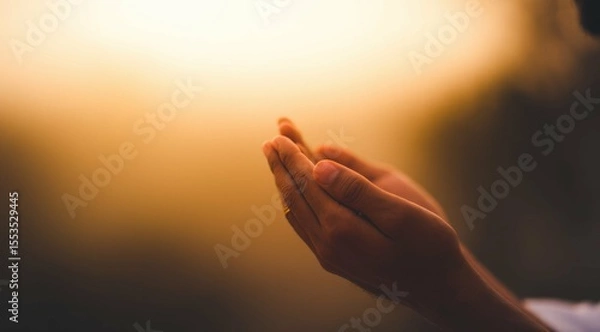 Obraz Man's cupped hands in prayer against a bokeh golden sunlight background.