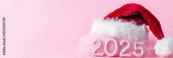 Fototapeta Santa hat resting on 3D fluffy 2025 over pink background, vibrant Christmas and New Year image for seasonal graphics