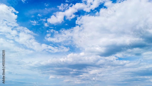 Obraz Vast blue sky filled with fluffy white clouds during daytime, creating a serene atmosphere. Ideal for backgrounds, nature themes, and weather-related concepts.