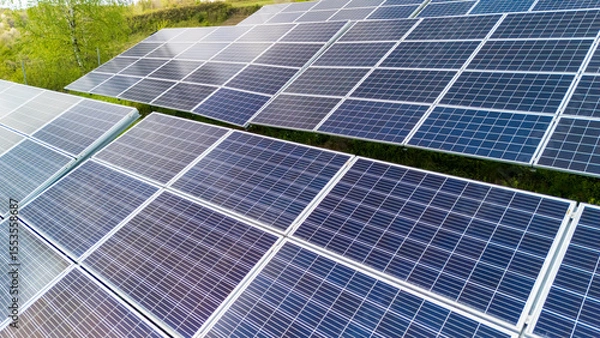 Obraz Aerial view of solar panels arranged in rows, capturing sunlight in a green environment. This image showcases renewable energy production and sustainable technology.