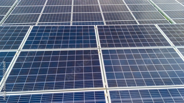 Obraz Aerial view of a large solar panel installation, showcasing a grid of photovoltaic panels capturing sunlight for renewable energy production in a sunny environment.