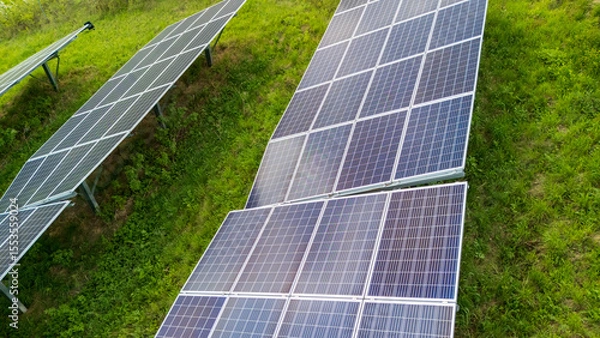 Obraz Aerial view of solar panels installed on a grassy slope. This renewable energy source demonstrates sustainability and innovation in technology.