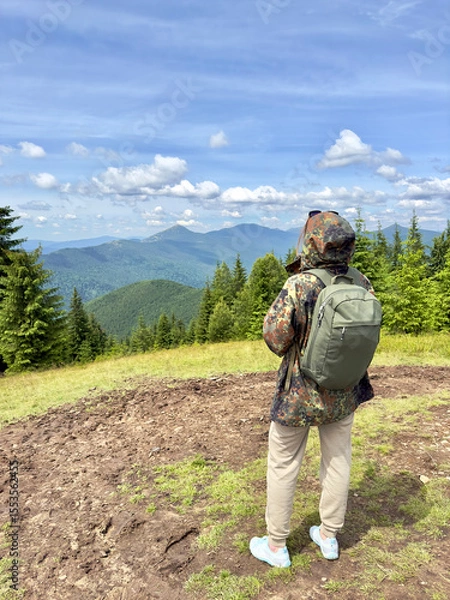 Obraz Reaching the summit.Woman hiker with backpack admiring the stunning panoramic mountain view from a summit. Concept of adventure, summer travel.Freedom and exploration.Active lifestyle and recreation